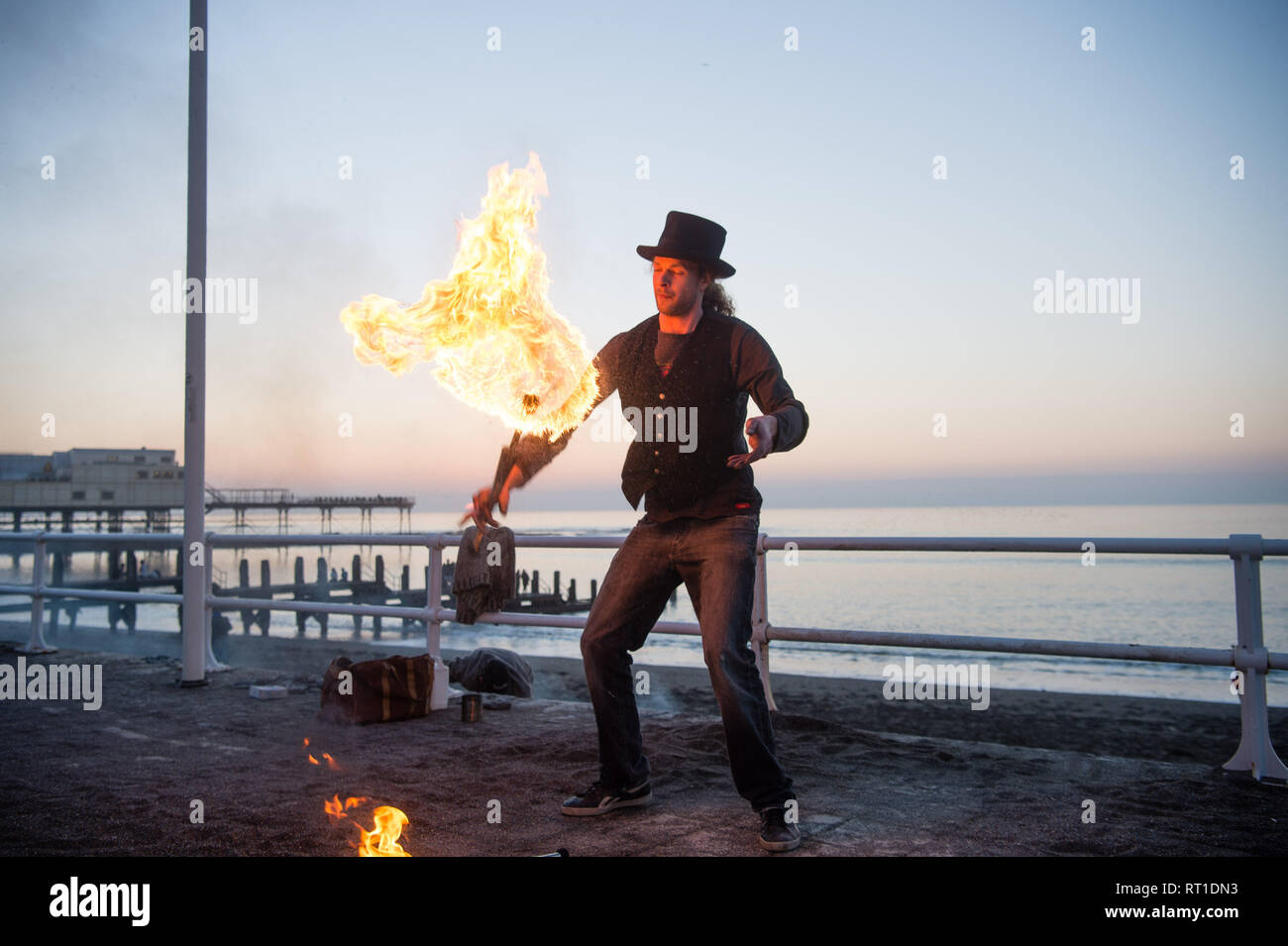 Aberystwyth Wales UK Mittwoch, den 27. Februar 2019. UK Wetter: ein Mann Jonglieren mit Feuer an der Promenade Aberystwyth, wie die Sonne, die die meisten der sensationell heiß und sonnig, 'Winter' Wetter, während es dauert. Das Wetter Prognose zu starten ab morgen zu verschlechtern, mit mehr typische windig und kühler Anfang März Foto Keith Morris/Alamy Live Nachrichten erwartet Stockfoto