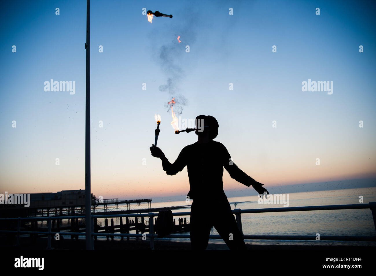 Aberystwyth Wales UK Mittwoch, den 27. Februar 2019. UK Wetter: ein Mann Jonglieren mit Feuer an der Promenade Aberystwyth, wie die Sonne, die die meisten der sensationell heiß und sonnig, 'Winter' Wetter, während es dauert. Das Wetter Prognose zu starten ab morgen zu verschlechtern, mit mehr typische windig und kühler Anfang März Foto Keith Morris/Alamy Live Nachrichten erwartet Stockfoto