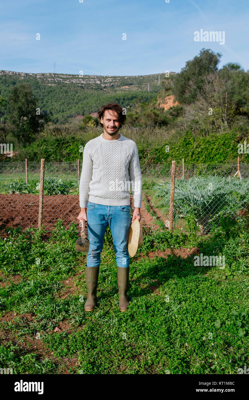 Junge Landwirt im Gemüsegarten mit Strohhut und eine Hacke Stockfoto
