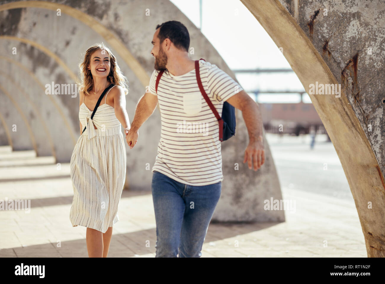 Spanien, Andalusien, Malaga, unbeschwerten touristische Paar unter einem Torbogen in der Stadt läuft Stockfoto