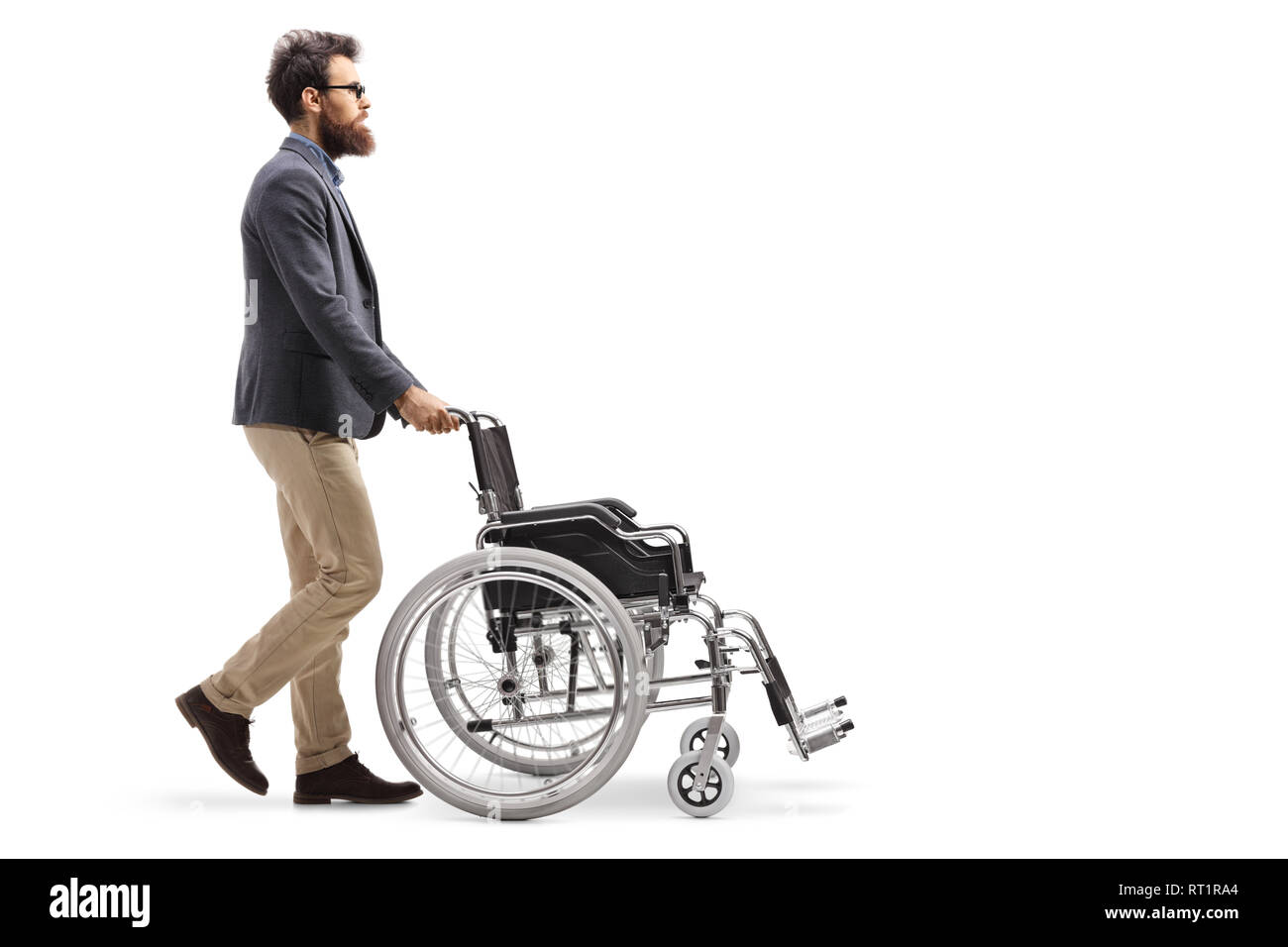 Volle Länge Profil Schuß eines bärtigen Mannes drückt einen leeren Rollstuhl auf weißem Hintergrund Stockfoto
