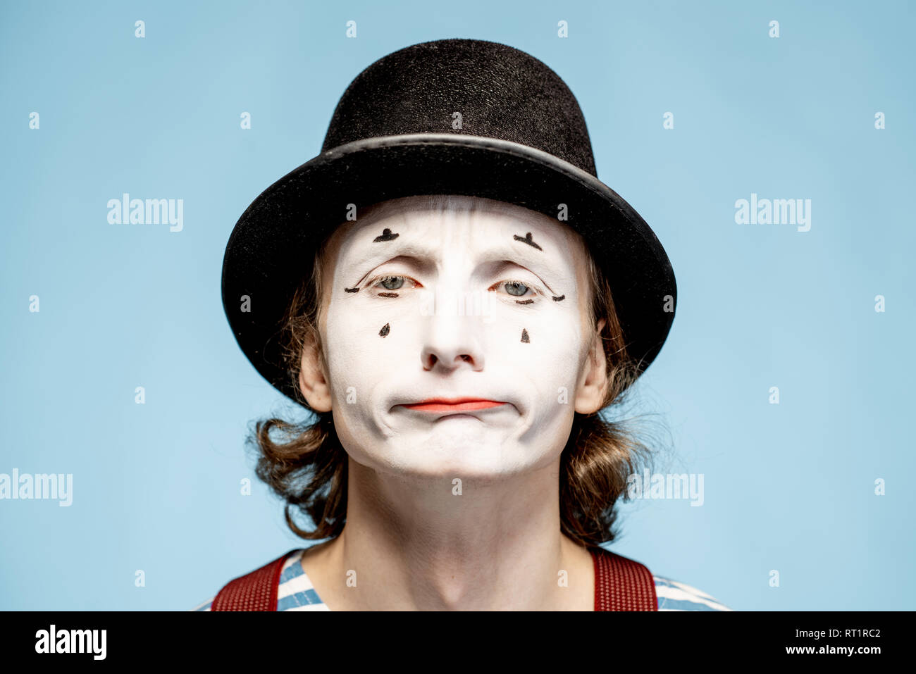 Nahaufnahme Porträt eines Schauspielers als Pantomime mit weißem Gesicht Make-up zeigt ausdrucksstarke Emotionen auf den blauen Hintergrund Stockfoto