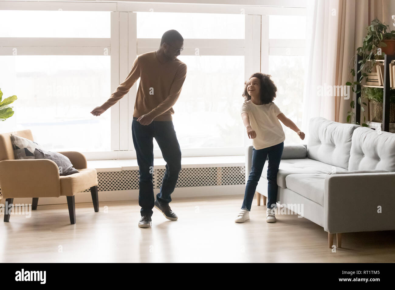 Happy afrikanischen Vater und Kind Tochter tanzen im Wohnzimmer. Stockfoto