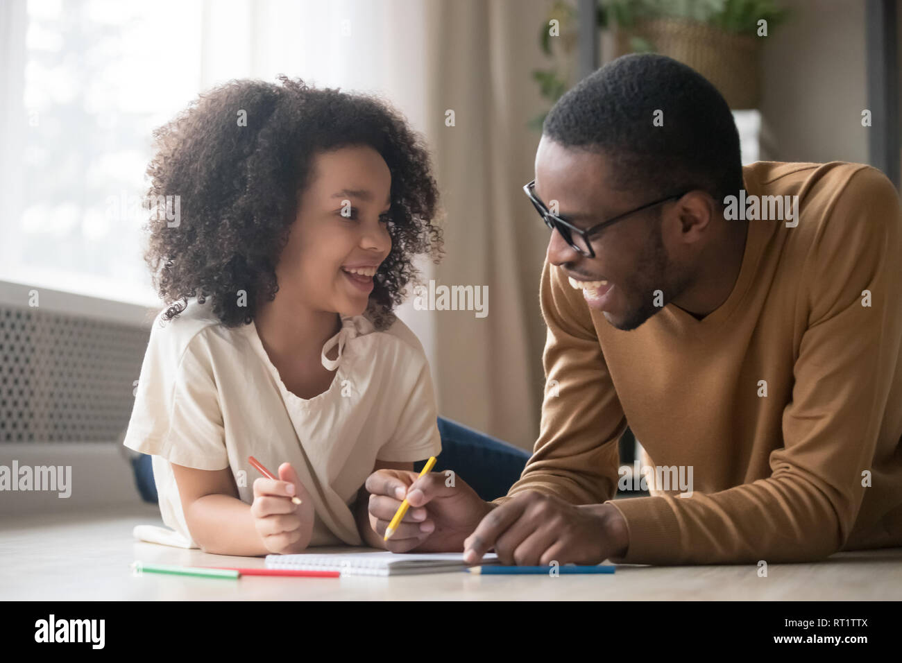 Afrikanisches kind Mädchen zeichnen mit bleistift Spaß mit Papa Stockfoto