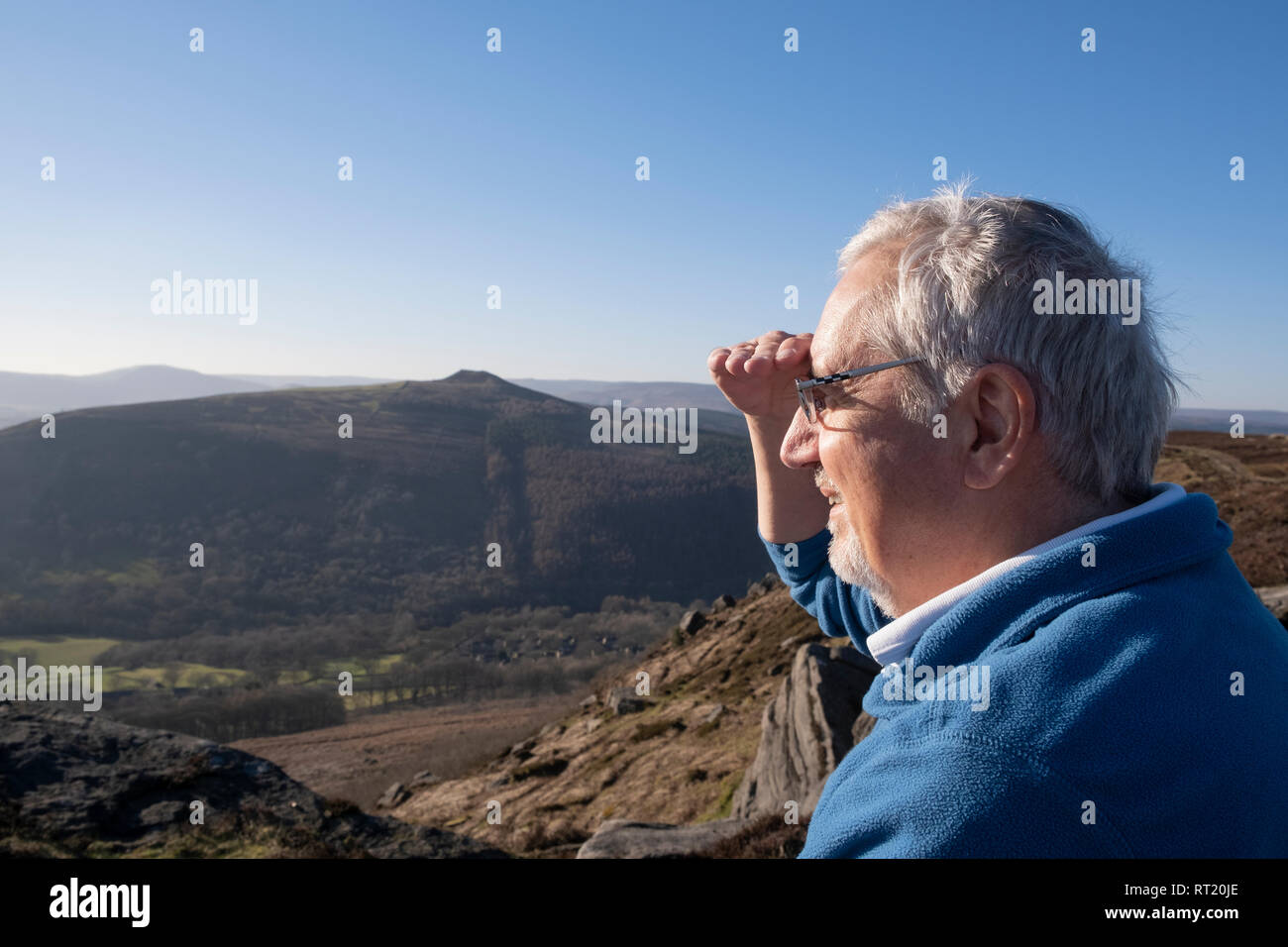 Älterer Mann in 60 s Schattierung seine Augen von strahlendem Sonnenschein mit Blick auf den ländlichen Winterlandschaft in Großbritannien Stockfoto