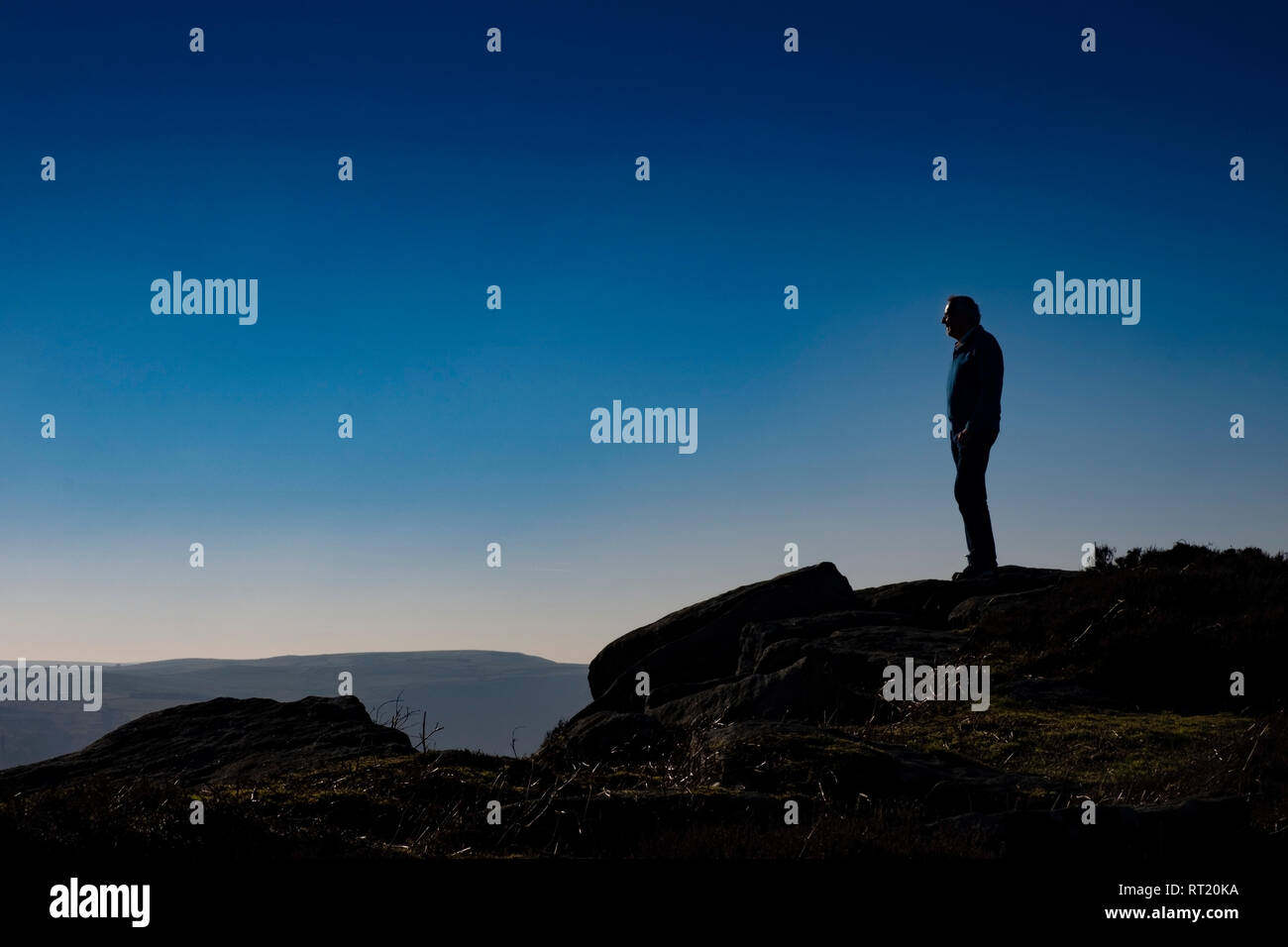 Älterer Mann stand auf der Klippe, 60 s Alter, Silhouette gegen den klaren Himmel Stockfoto
