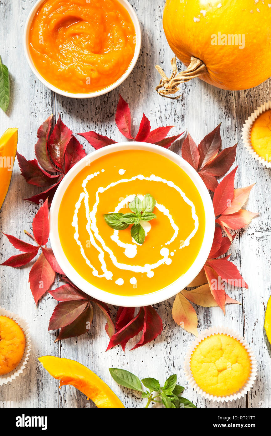 Kürbissuppe und Muffins mit dem trockenen Blätter im Herbst auf weißem Holz- Hintergrund Stockfoto