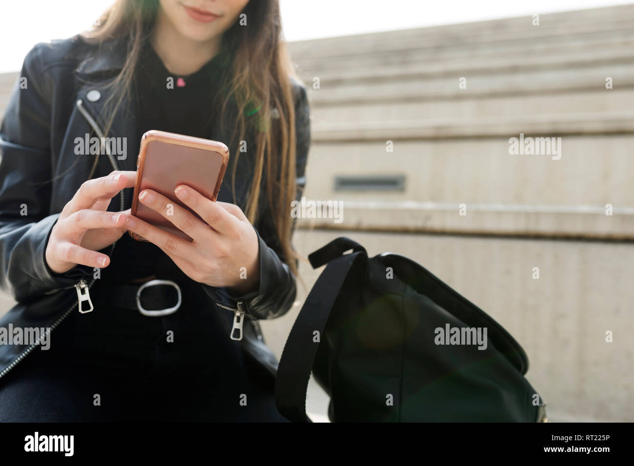 Close-up junge Frau sitzt auf der Treppe mit Handy Stockfoto