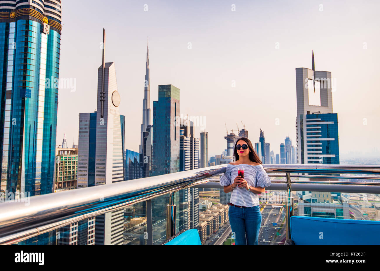 Frau mit einem Drink und Blick auf die Stadt Dubai genießen. Stockfoto