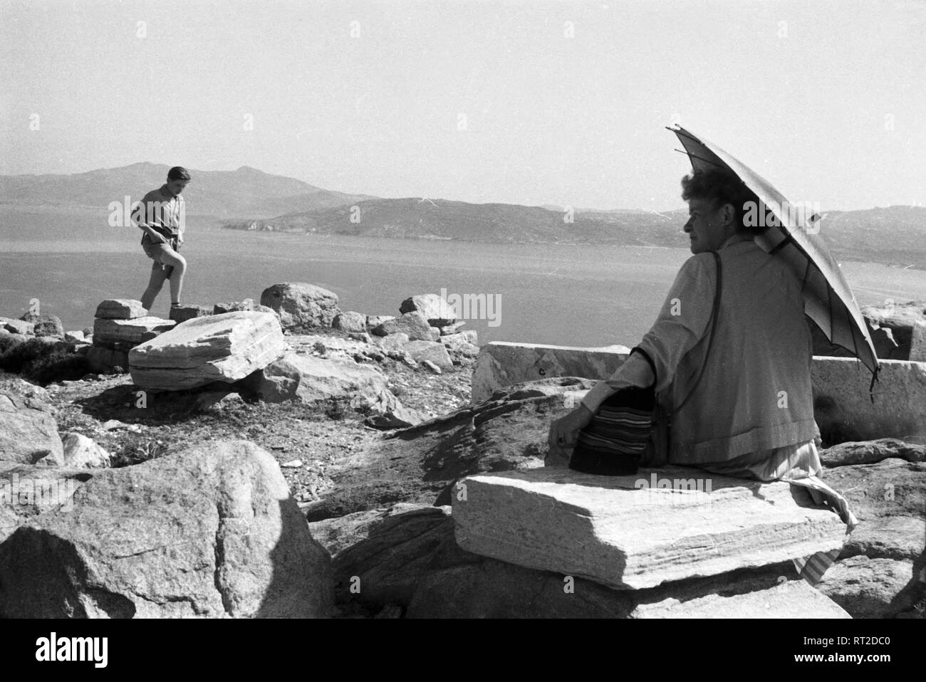 Spanien, Griechenland - eine Frau mit einem Sonnenschirm und Junge an den Klippen der Insel Delos, Panorama, 1950er Jahre. Eine Frau mit einem Regenschirm und ein Junge auf den Klippen der osland von Delos, Griechenland, 1950. Stockfoto