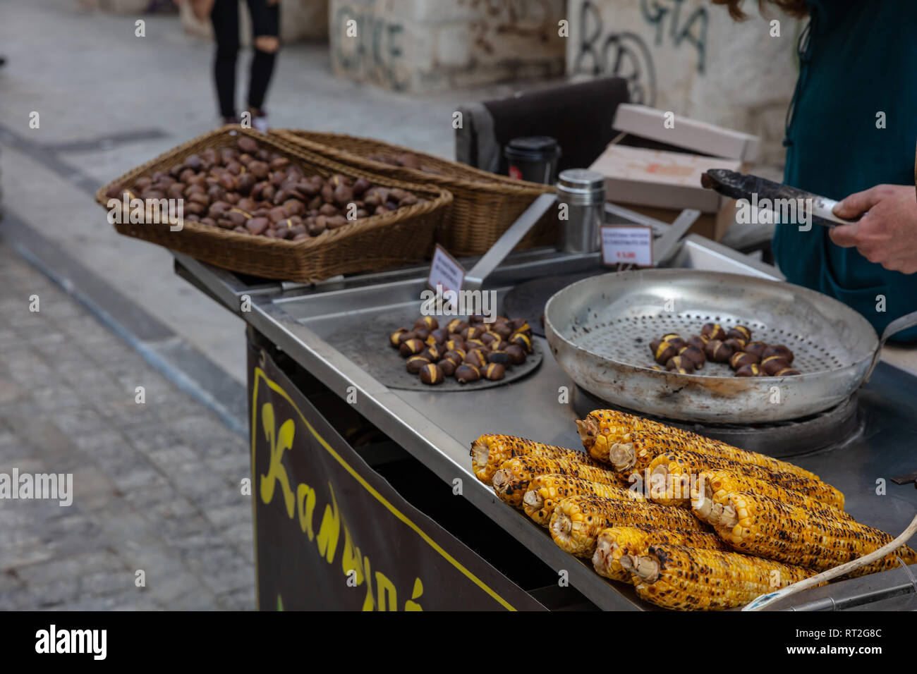 Street Food. Rösten und Verkauf von Süßen Hühneraugen und Kastanien an der Straße Ermou Athen, Griechenland. Stockfoto