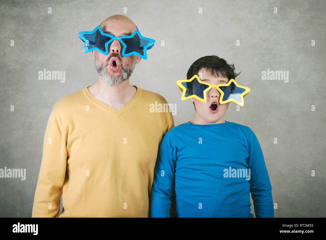 Vatertag, Vater und Sohn mit lustigen Sonnenbrille gegen grauer Hintergrund Stockfoto