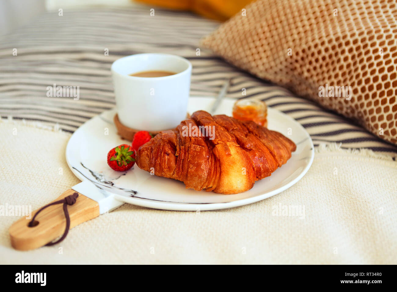 Frühstück mit Croissant, Kaffee, Erdbeere und Stau auf der Platte Fach im Bett. Ansicht von oben Stockfoto