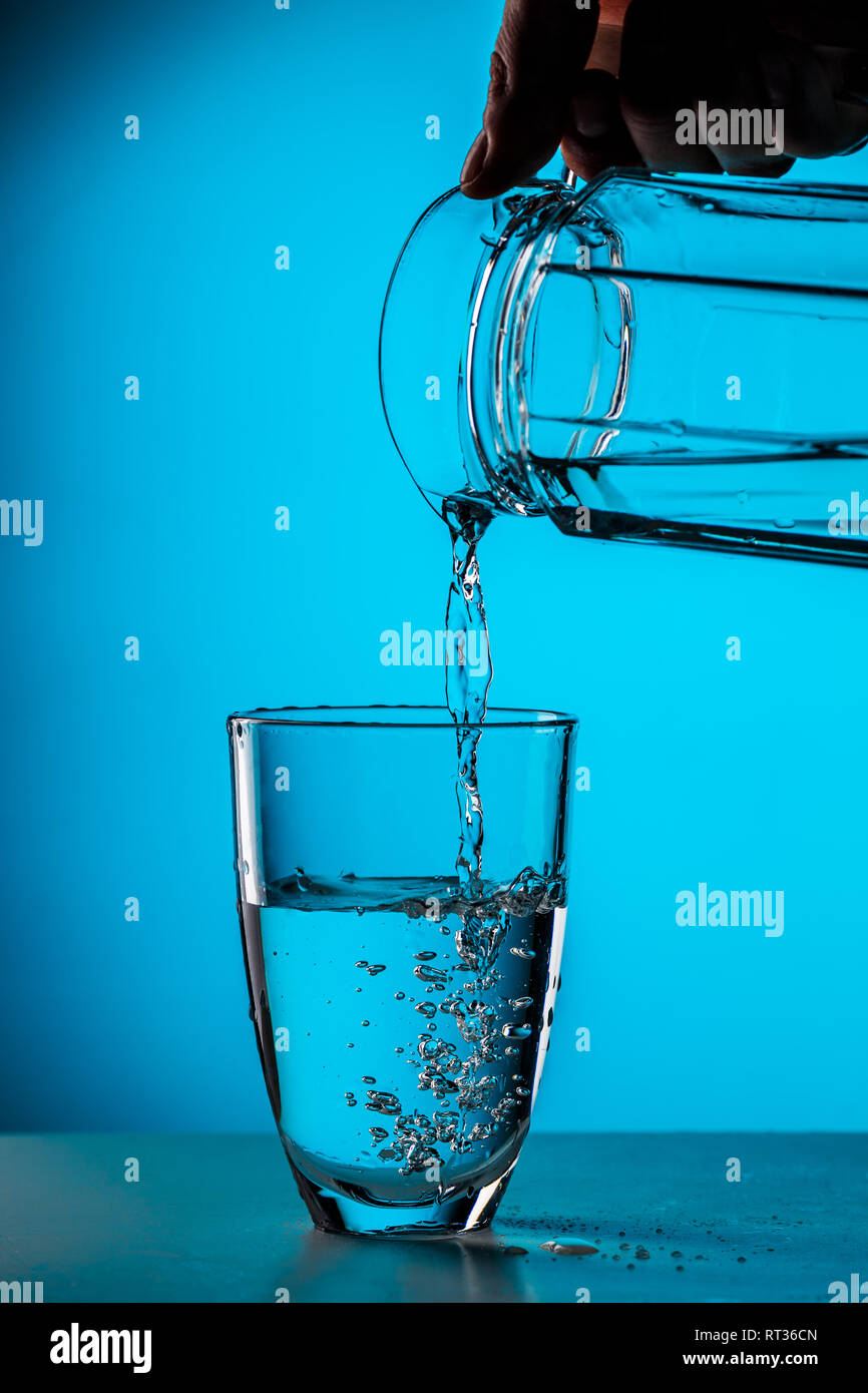 Man gießt Wasser aus Glas Stockfoto