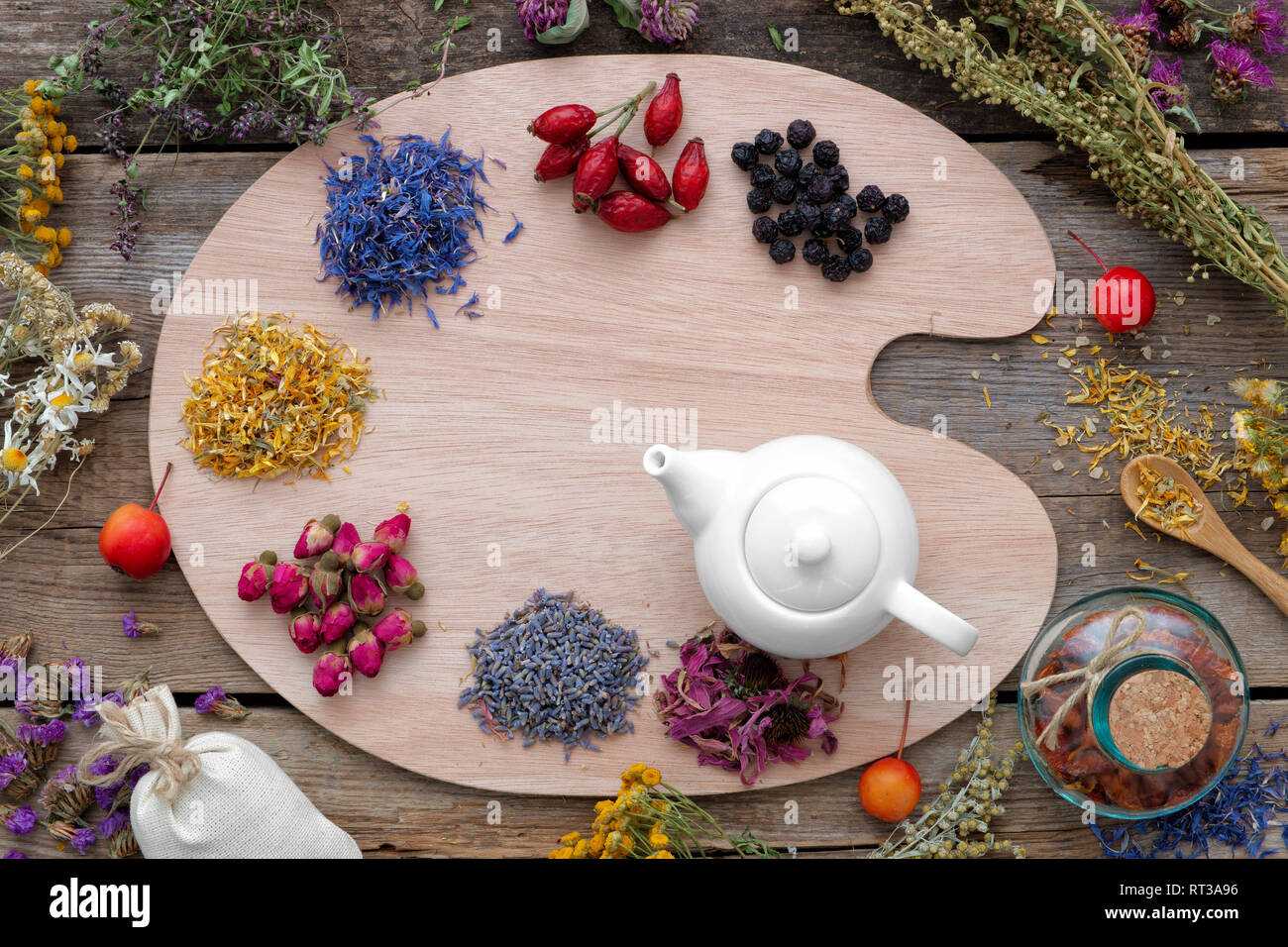 Heilkräuter auf Holzboden- und Teekocher, Ansicht von oben. Kräutermedizin Konzept. Stockfoto