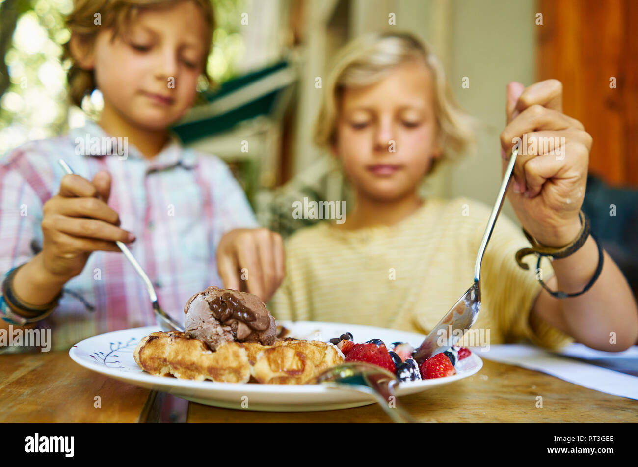 Zwei Jungen sitzen am Tisch essen Eis Stockfoto