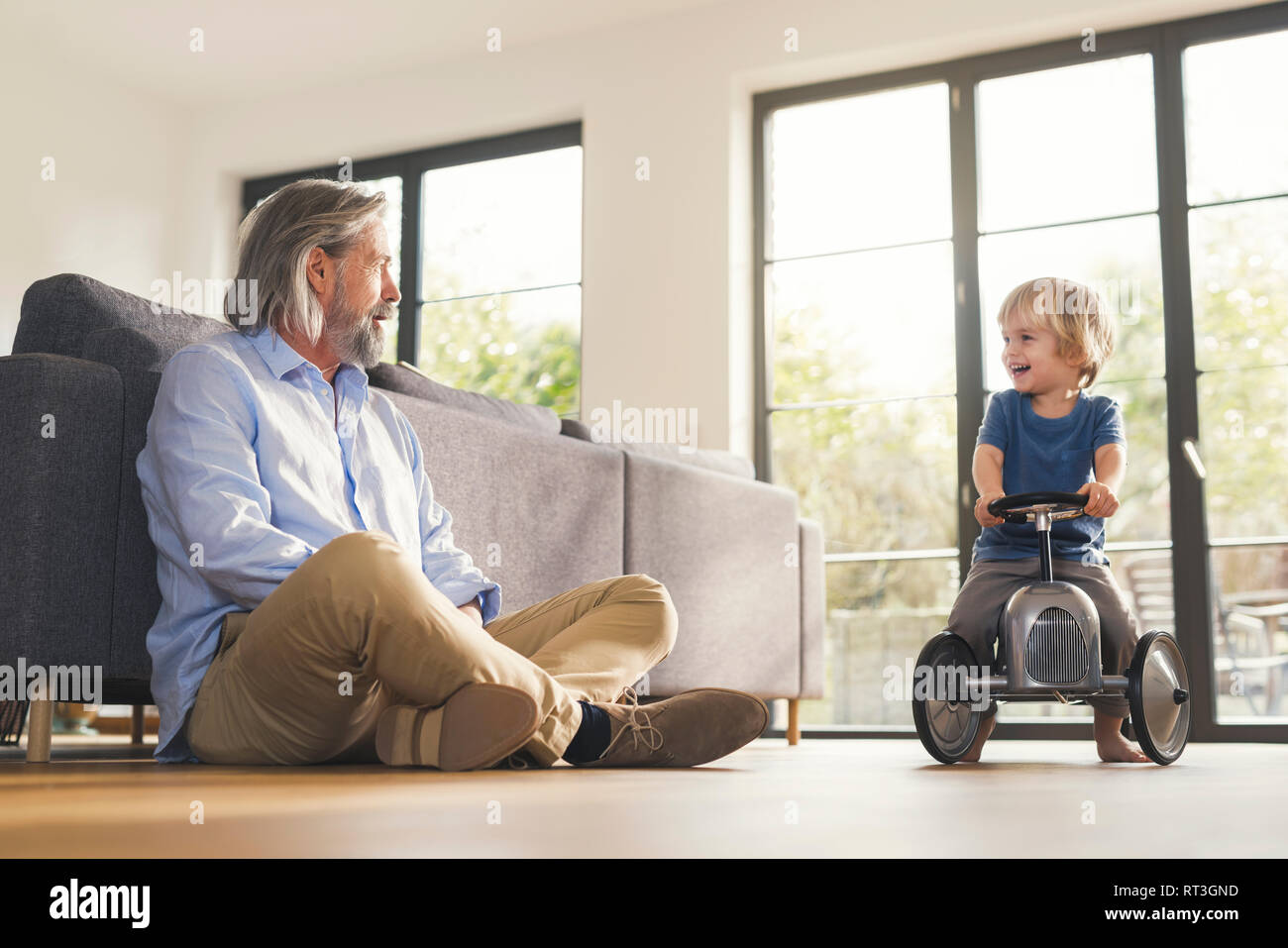 Großvater mit Enkel, sitzen auf spielzeugauto Stockfoto