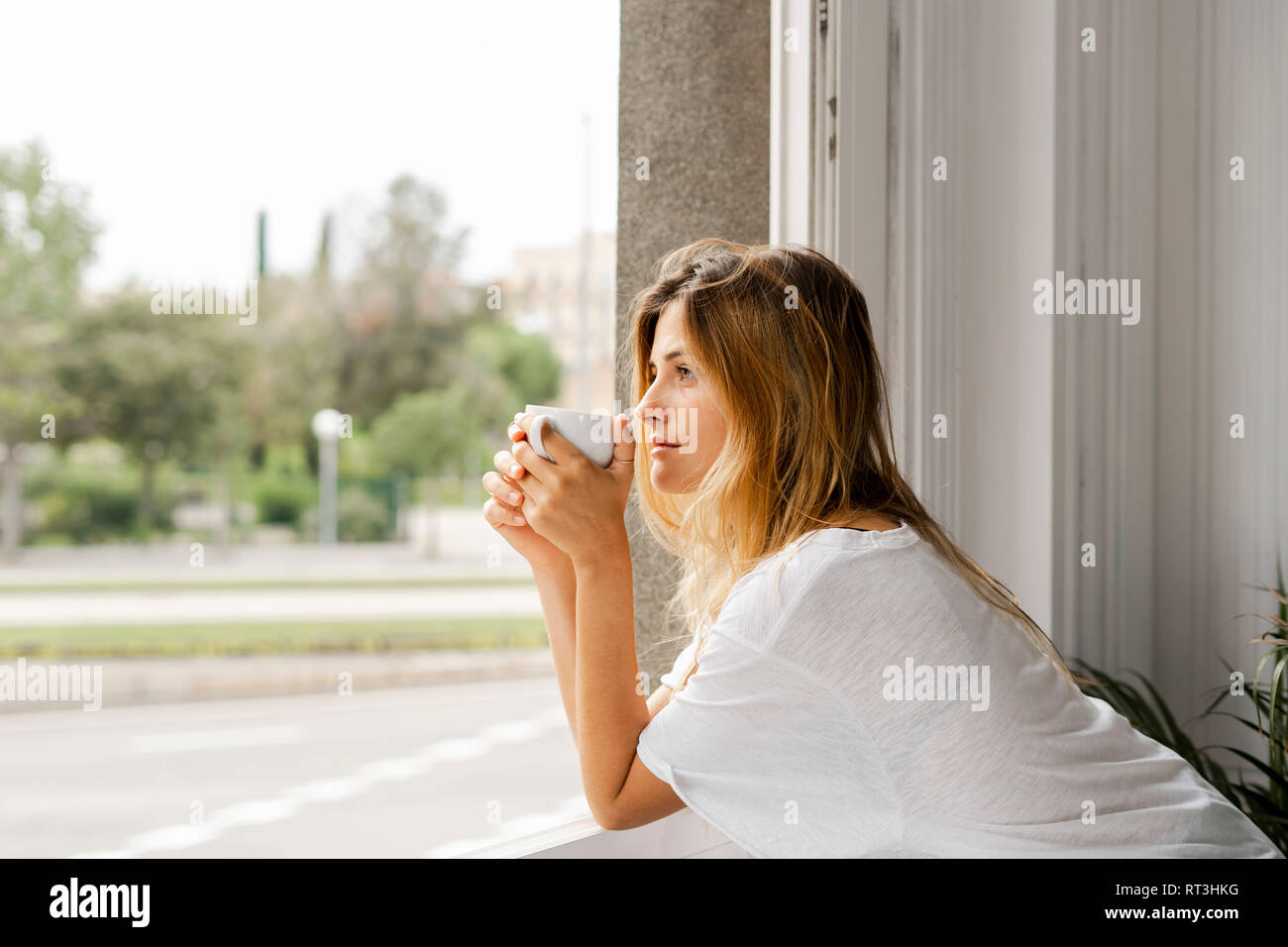 Junge Frau am Fenster holding Tasse Kaffee Stockfoto