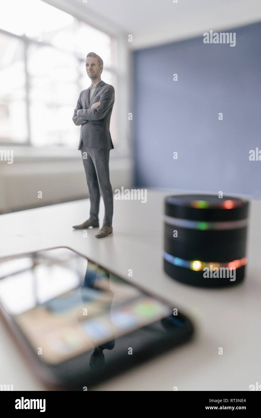 Miniatur Geschäftsmann Figur neben smart home Lautsprecher und Smartphone Stockfoto