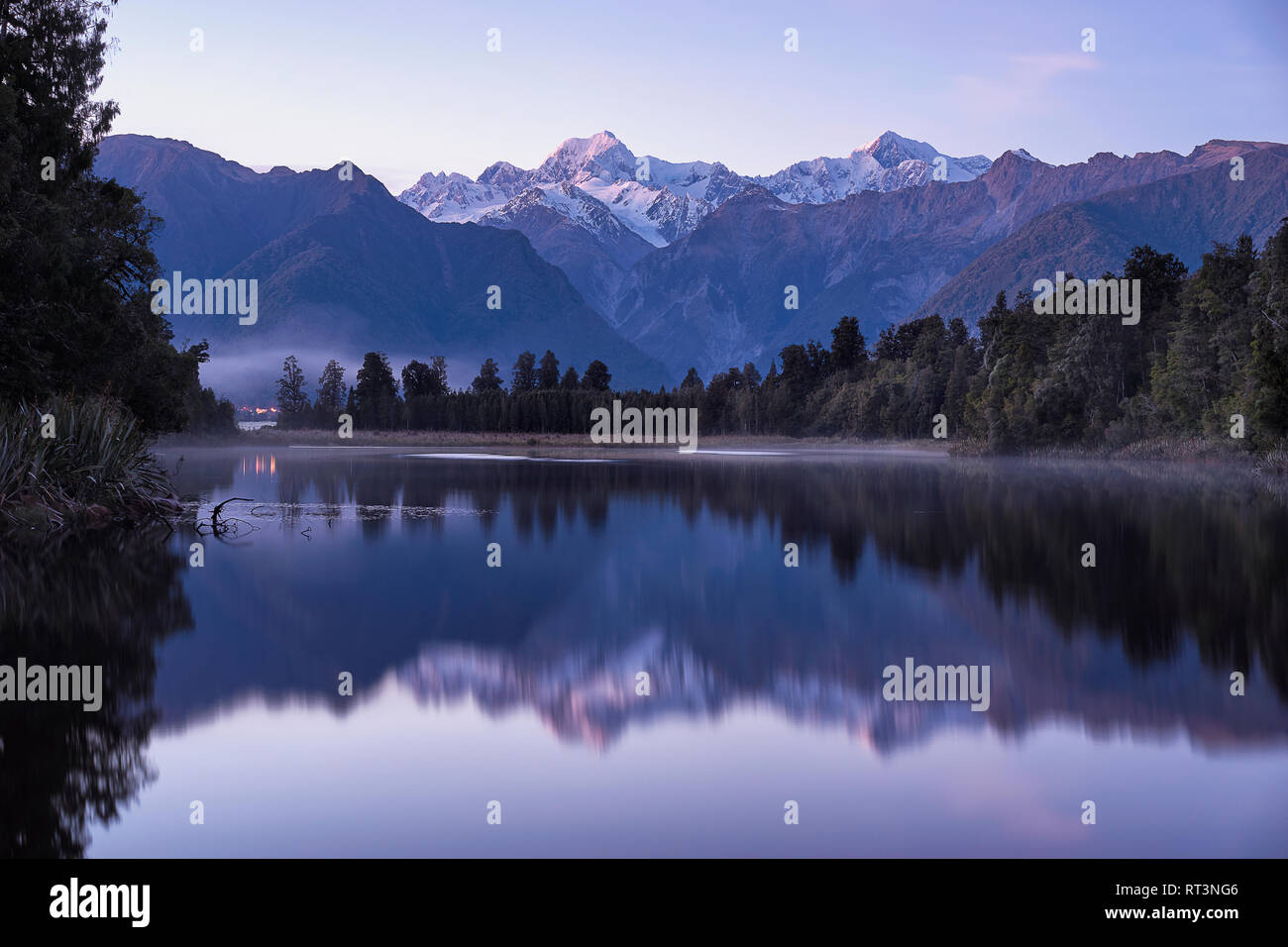 Große winter Panorama der Lake Matheson. Lila morgen Szene von Neuseeland. Dramatische morgen ansehen und spektakulären Winter Sonnenaufgang. Stockfoto