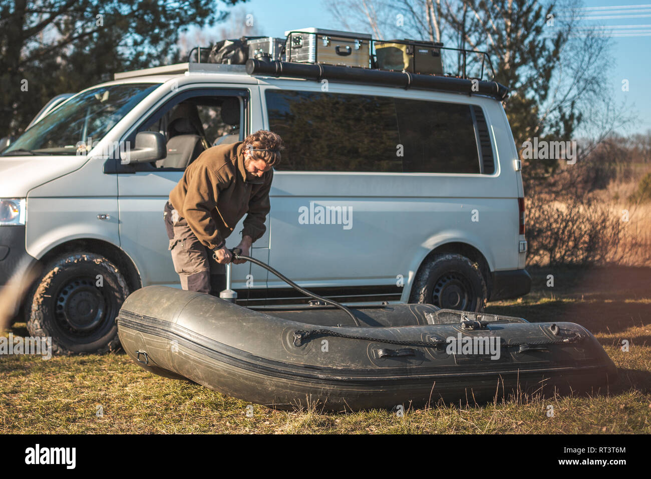 Mann vor ein Transporter in der Natur geparkt ist Aufpumpen eines Schlauchboot zum Angeln Stockfoto