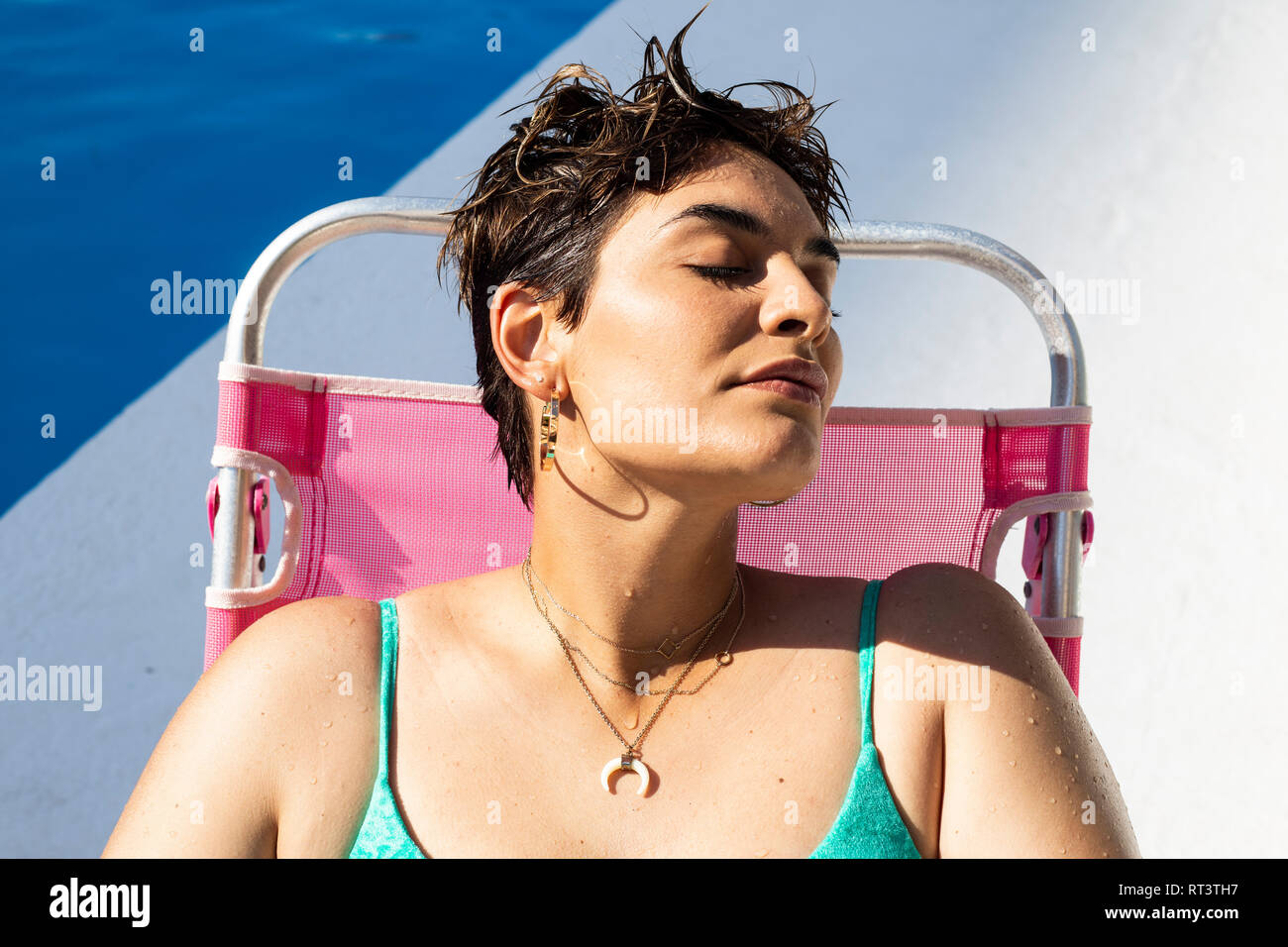 Porträt der jungen Frau, entspannend, auf der Sonnenliegen am Pool Stockfoto