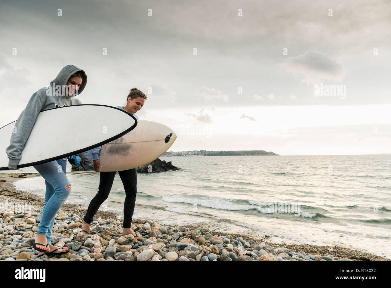 Gerne Freunde mit Surfbrett zu Fuß auf steinigem Strand Stockfoto