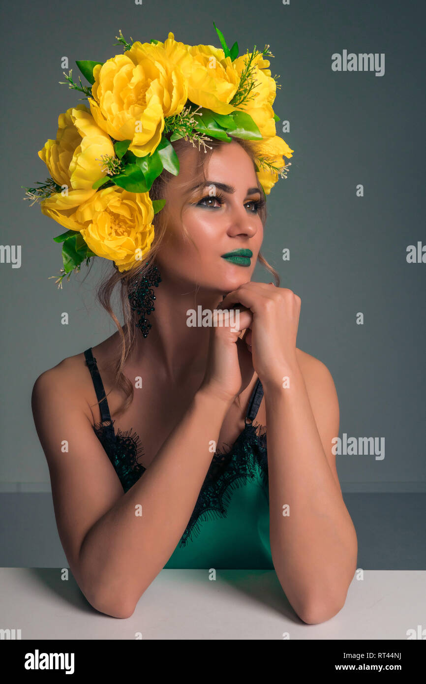 Porträt einer nett Schön blond mit einem Rand von gelben Blumen und helles Make-up auf einem dunklen Hintergrund Stockfoto