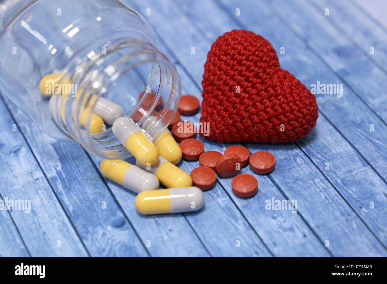 Pillen und roten Herzen auf Blau gestrickt Holztisch. Konzept der Hypertonie, Gesundheitswesen, Behandlung von Herzkrankheiten, Beruhigungsmittel, Ischämie Stockfoto