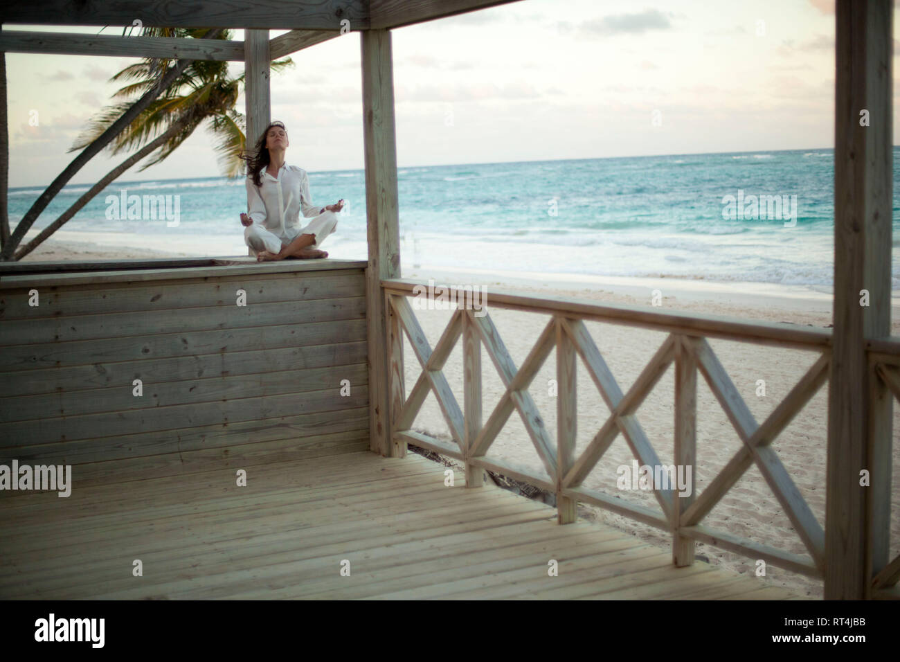 Eine junge schöne Frau in weißen Kleidern sucht, ihren Frieden im Sonnenuntergang in einem tropischen Strand Stockfoto