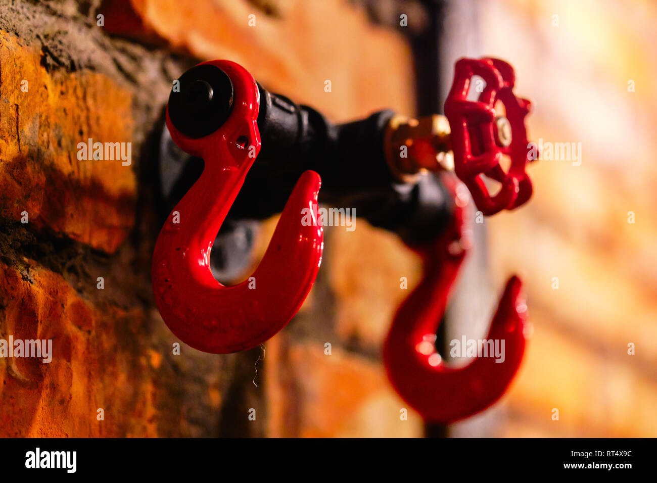 Close up Rot riesig große Haken Bügel oder Rack für Kleidung auf Stein steinigen Mauer im Cafe Bar pub Garderobe. Steampunk Design Element Stockfoto