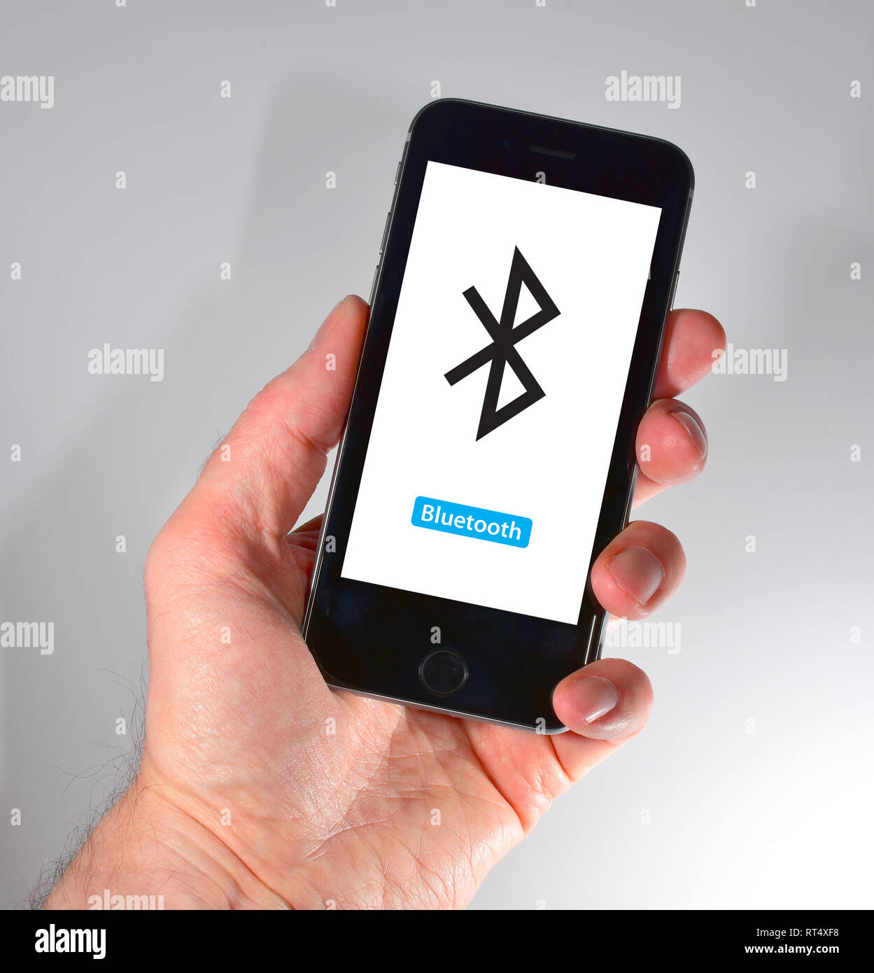 Das iPhone in der Hand gehalten - Bluetooth Symbol Stockfoto