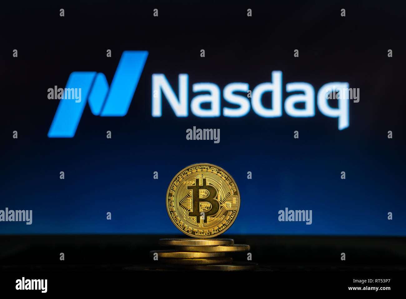 Bitcoin auf einem Stapel von Münzen mit Nasdaq Logo auf einem Laptop. Annahme blockchain Cryptocurrency und Mainstream. Slowenien - 02 24 2019 Stockfoto