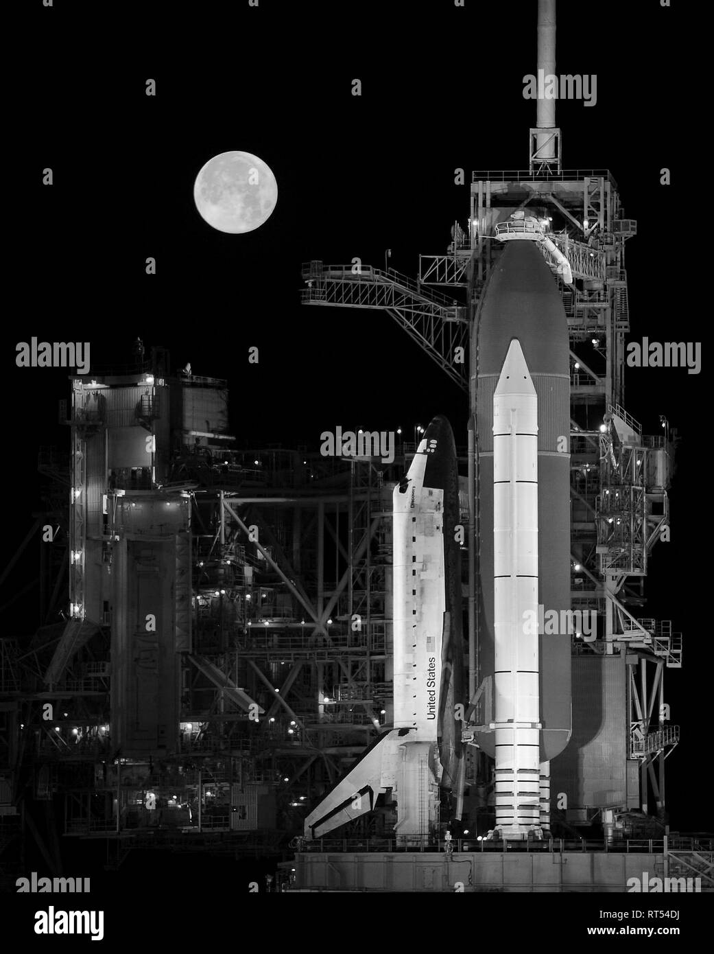 Space Shuttle Discovery sitzt auf dem Launch Pad mit einem Vollmond im Hintergrund. Stockfoto