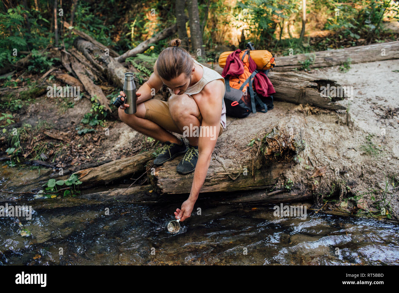 Junge Wanderer scooping frisches Wasser in einem Wald Stockfoto