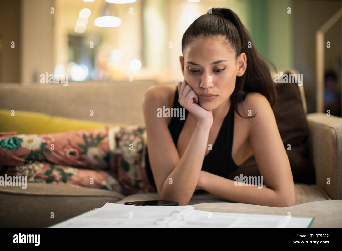 Frau im Schlafanzug Schreibarbeit Lesung am Wohnzimmer Sofa gerichtet Stockfoto