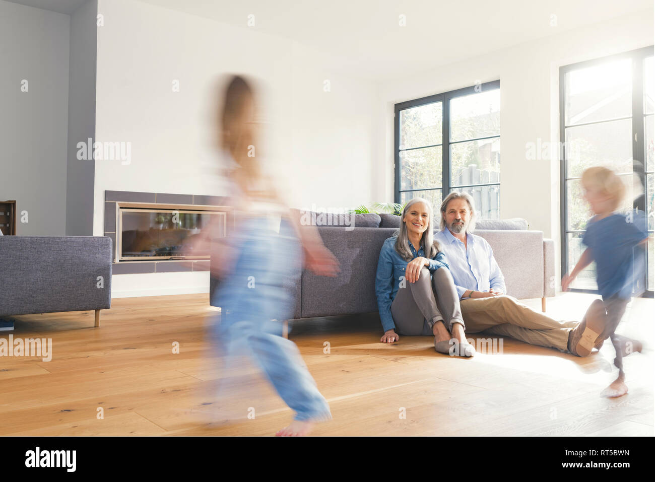 Großeltern, Enkelkinder beobachten, im Wohnzimmer spielen Stockfoto