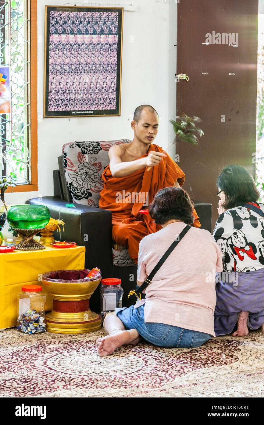 Mönch Segen Frauen mit Weihwasser, Dhammikarama Burmese Buddhist Temple, Georgetown, Penang, Malaysia. Stockfoto