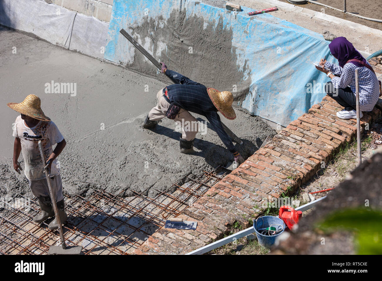 Junge malaysische Frau Überwachung Arbeiter mit Zement, Fort Cornwallis, Georgetown, Penang, Malaysia Stockfoto