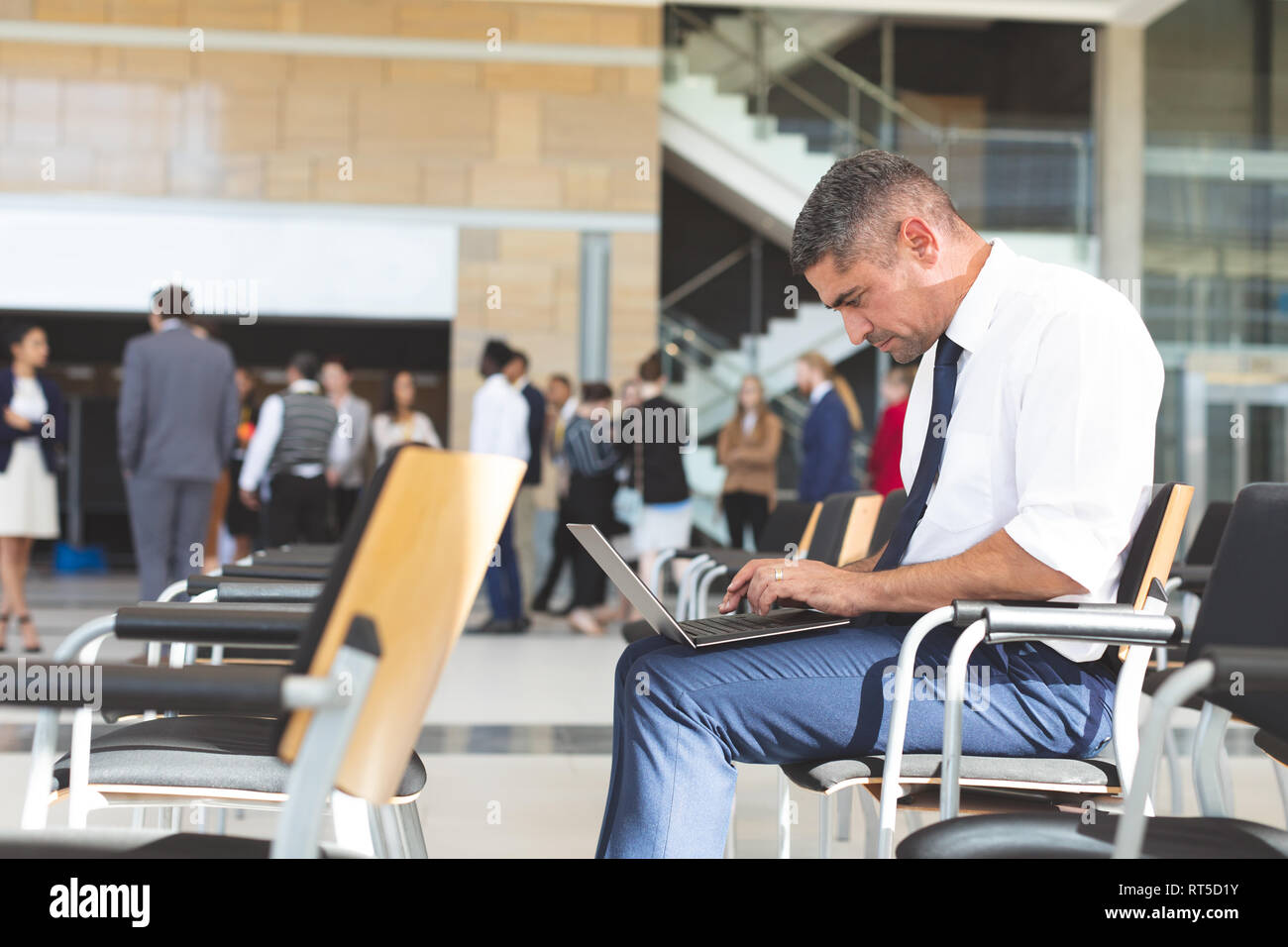 Geschäftsmann sitzt auf einem Stuhl und mit Laptop im Konferenzraum Stockfoto