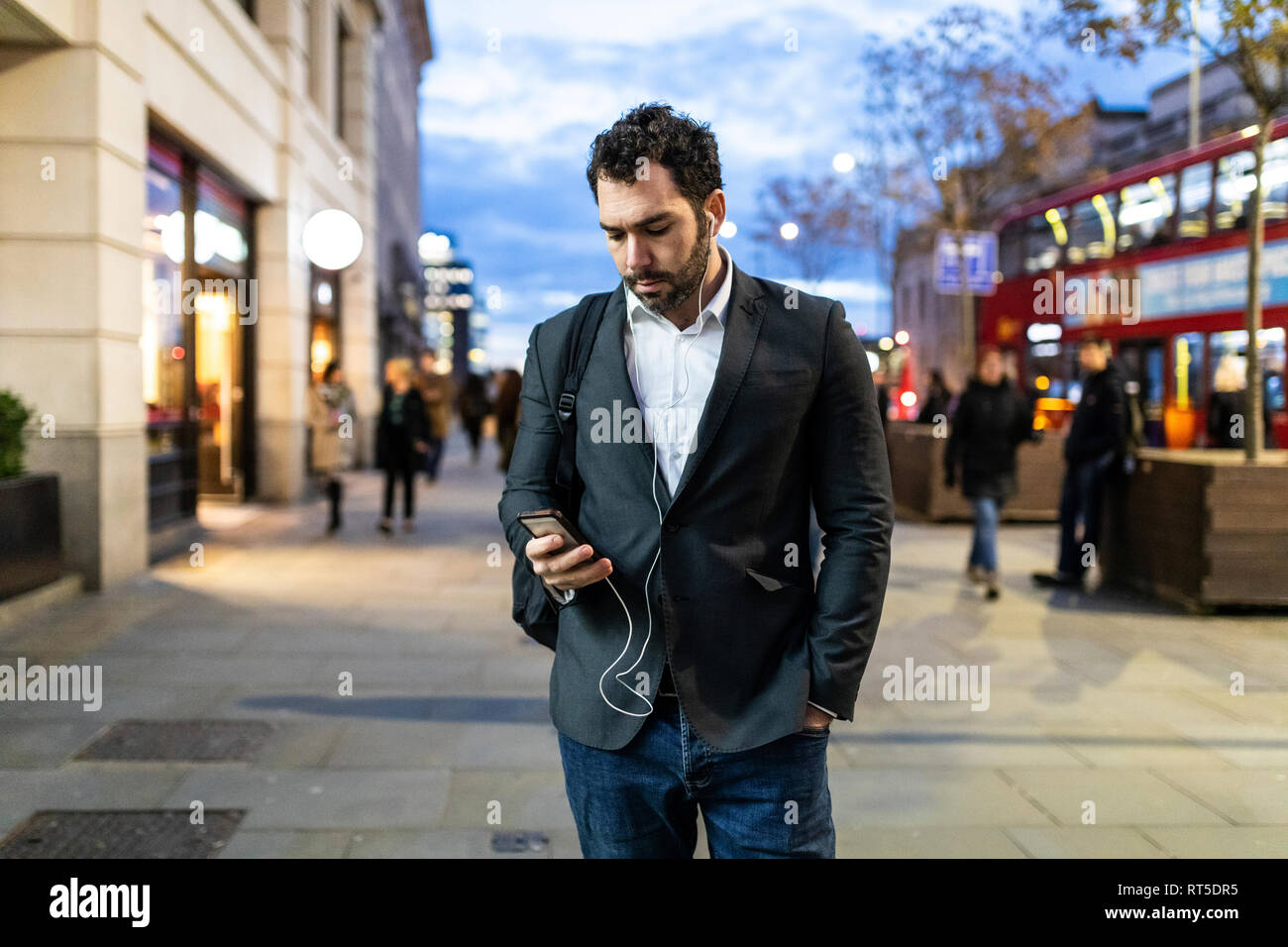 UK, London, Geschäftsmann auf seinem Telefon während der Nacht pendeln Stockfoto