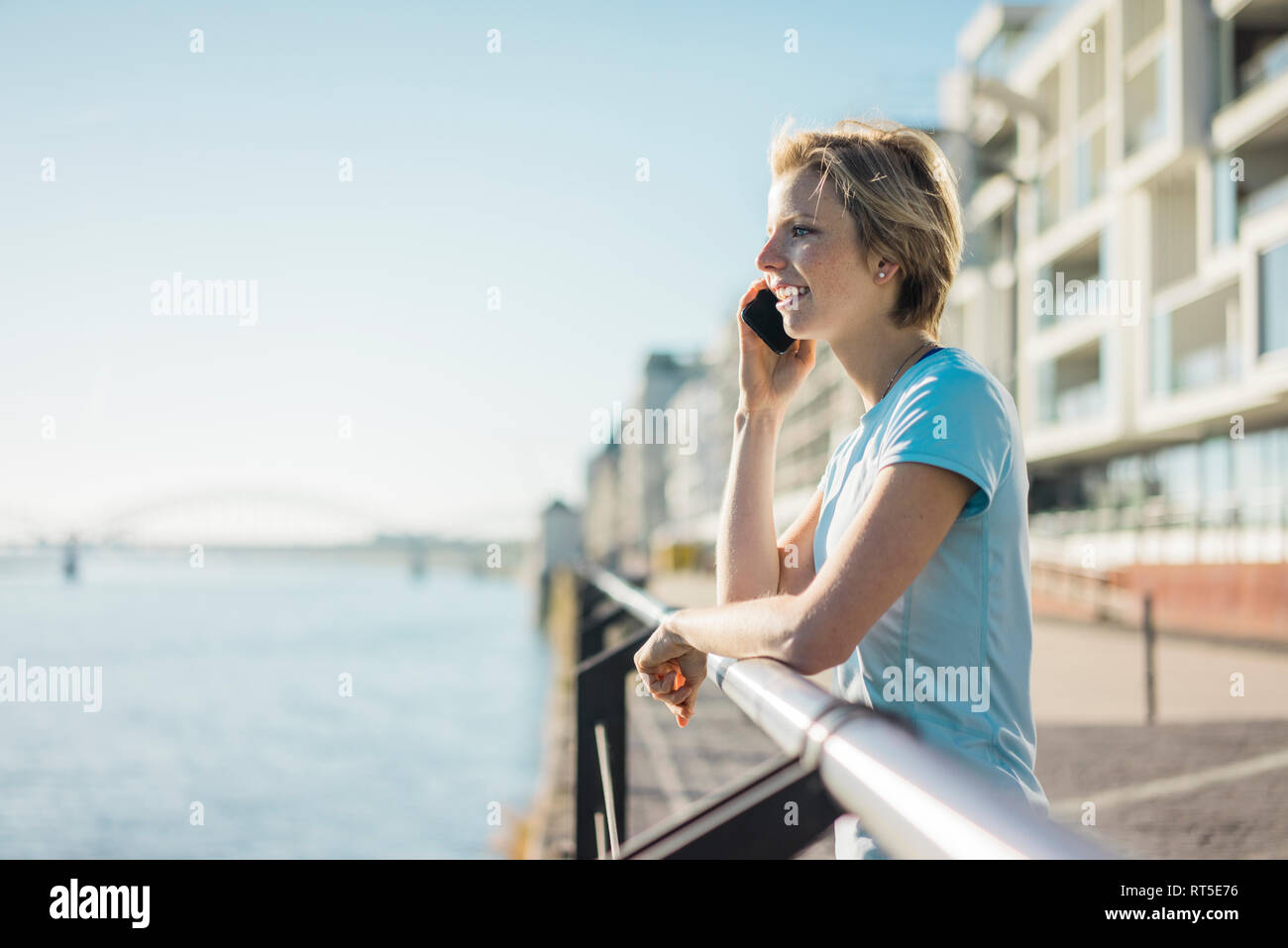 Junge Frau, die am Flußufer, die Sonne geniessen, am Telefon zu sprechen Stockfoto