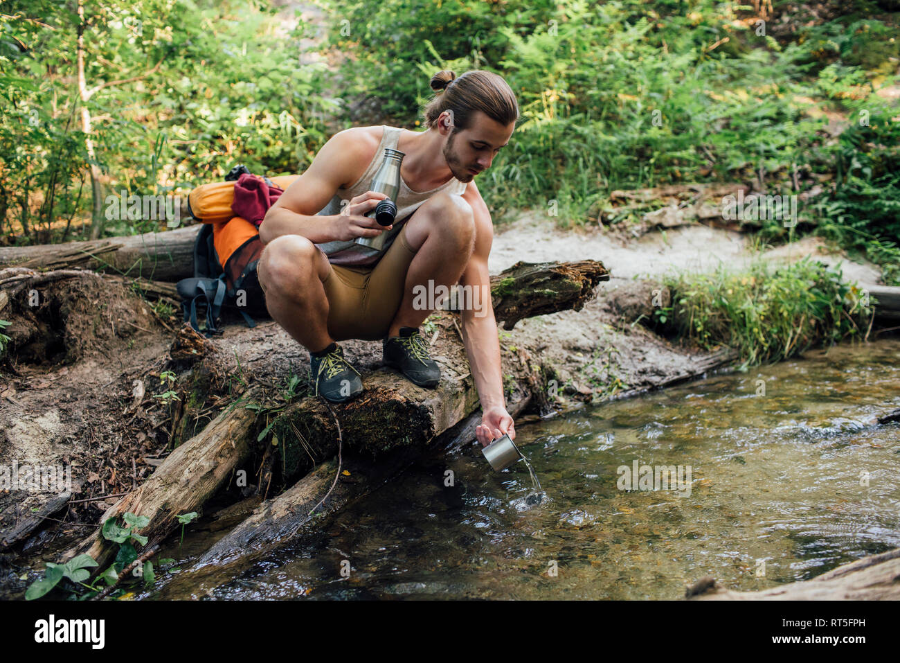 Junge Wanderer scooping frisches Wasser in einem Wald Stockfoto