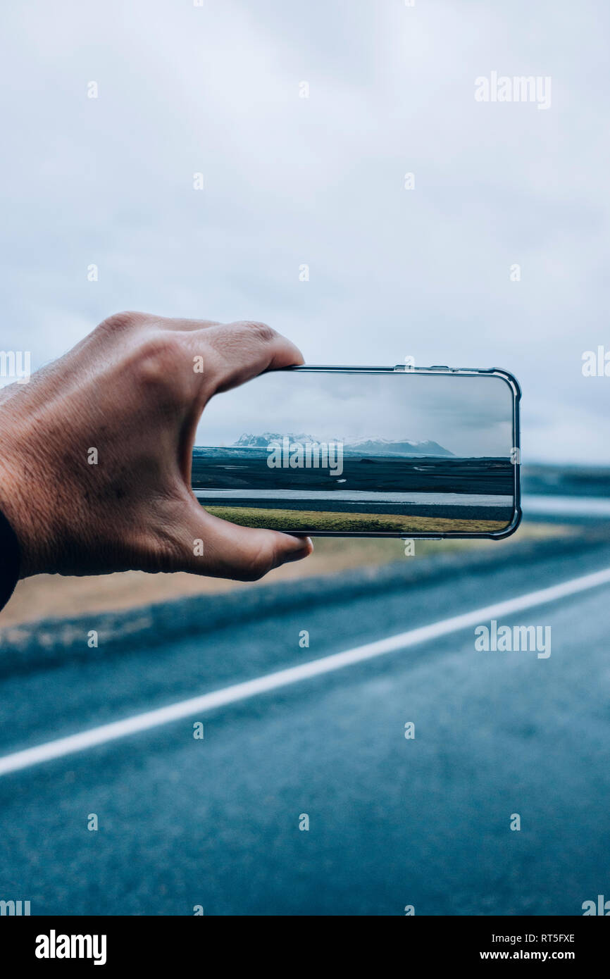 3D-Montage der Mann unter Smartphone Bild der isländischen Landschaft Stockfoto