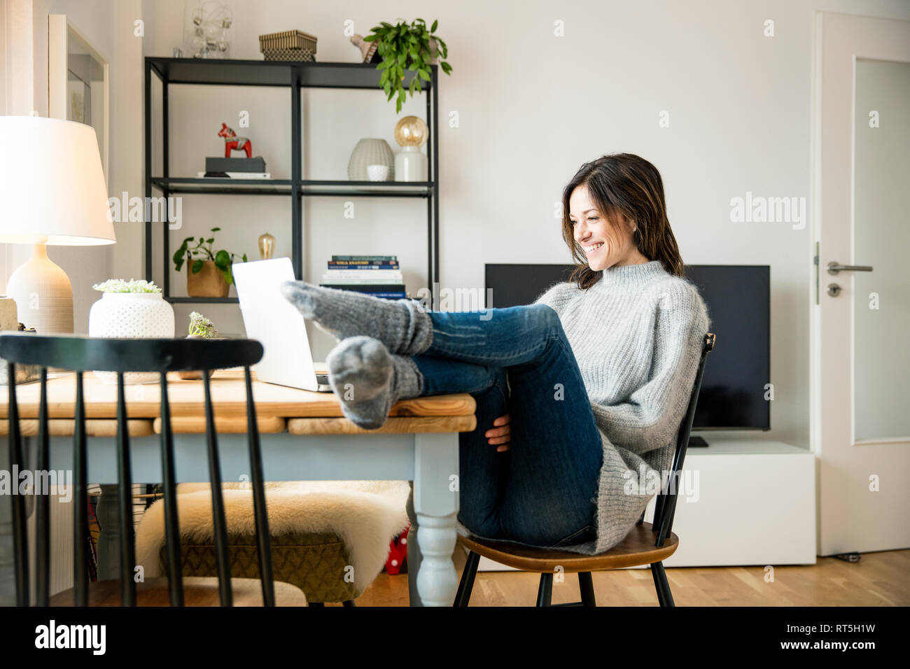 Frau sitzt am Tisch mit Füßen, mit Laptop Stockfoto