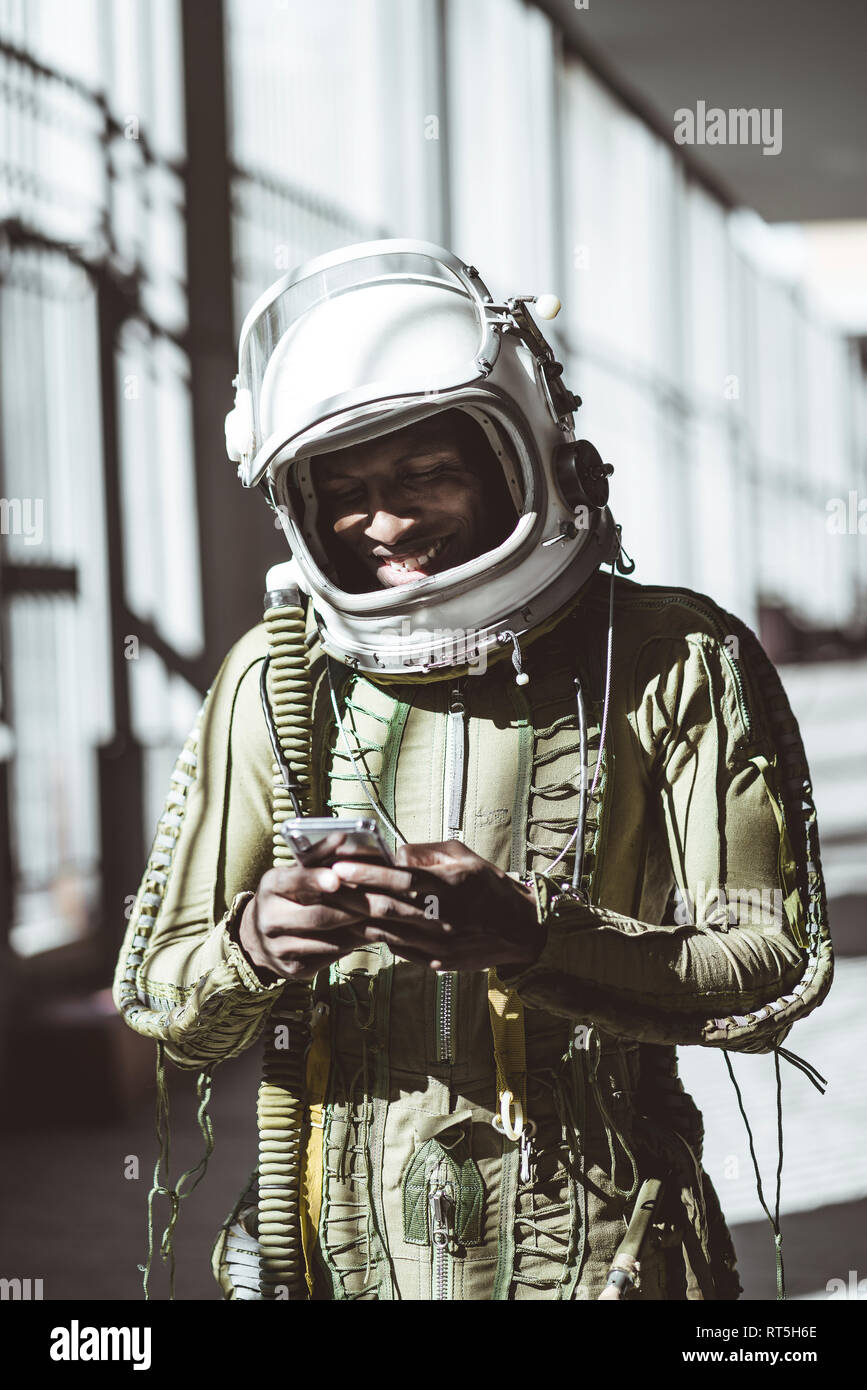 Lächelnd astronaut im Raumanzug mit Smartphone Stockfoto