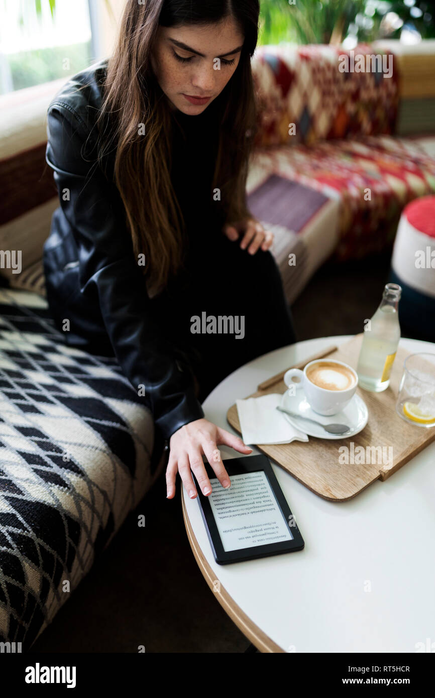 Junge Frau sitzt in einem Cafe mit e-book Stockfoto