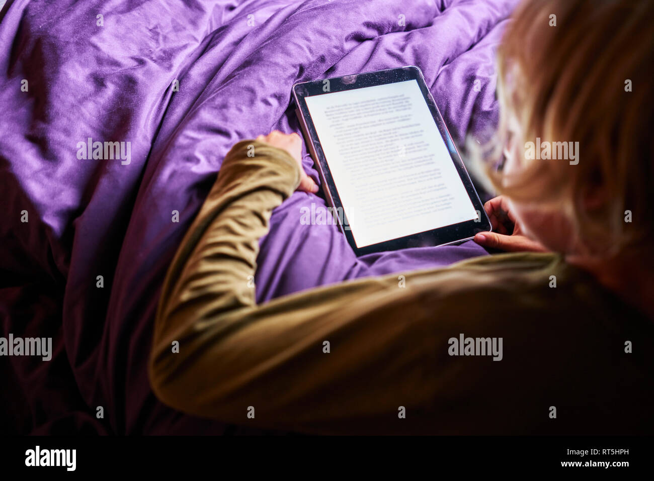 Junge lesen e-book auf Tablet im Bett Stockfoto