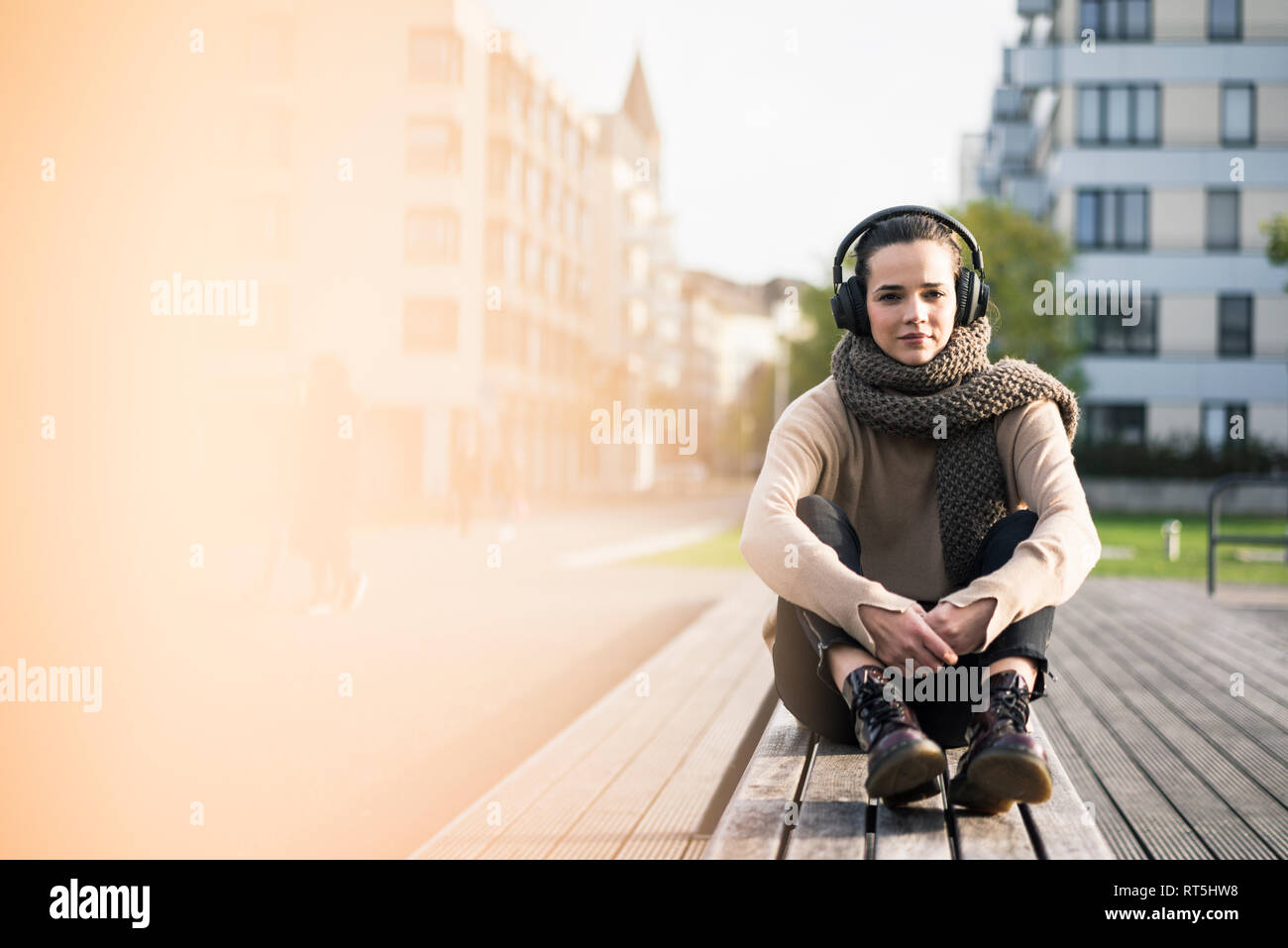 Portrait von Frau sitzt auf der Bank im Herbst Musik hören mit kabelloser Kopfhörer Stockfoto