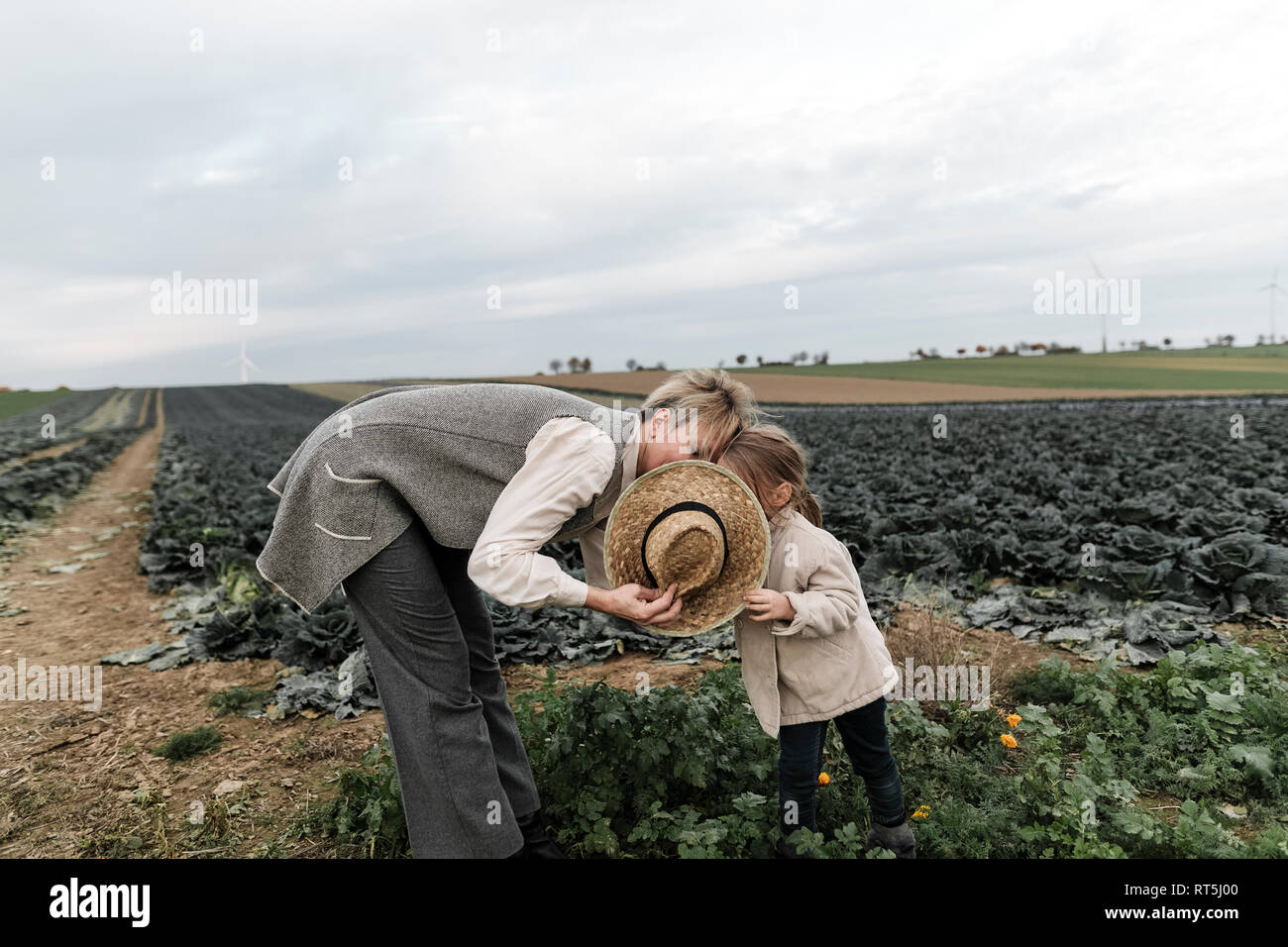 Mädchen und ihre Mutter mit Strohhut auf ein Kohl Feld Stockfoto